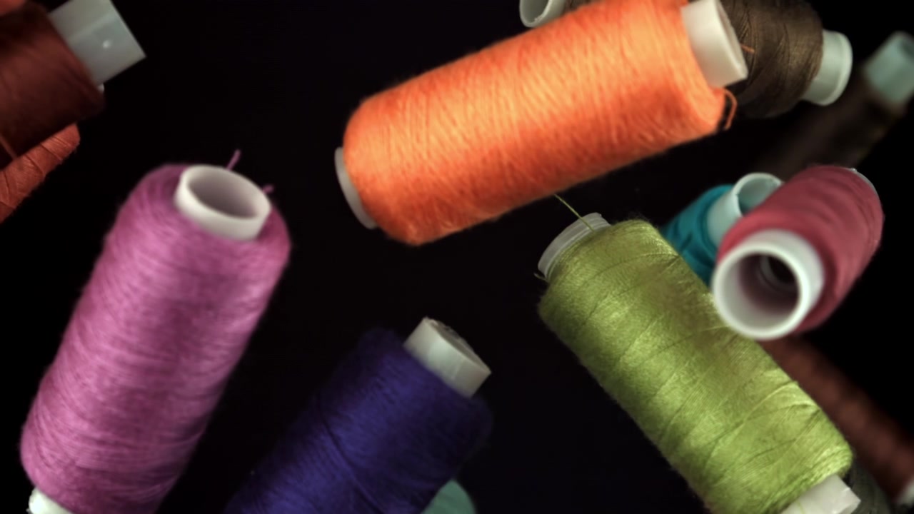 Close-Up of Multicolored Sewing Thread Spools on Black Background