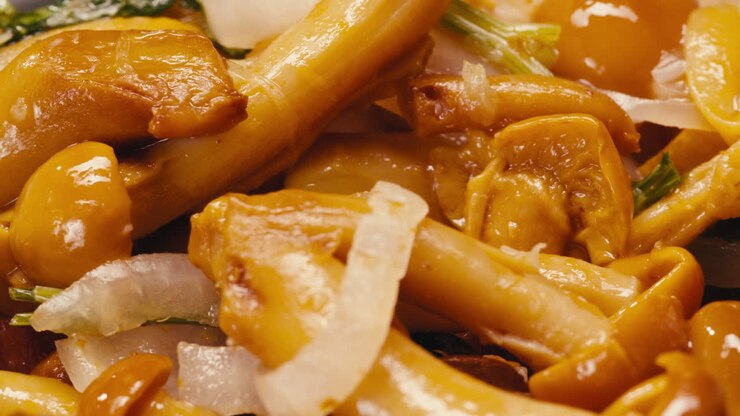 Primo piano di funghi gialli fermentati con cipolla su un piatto. Conservazione di verdure in barattoli di vetro. Fungo conservato per fermentazione con spezie, macro in rotazione.