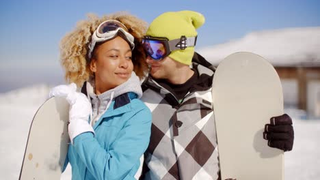 affectionate young couple posing with snowboards