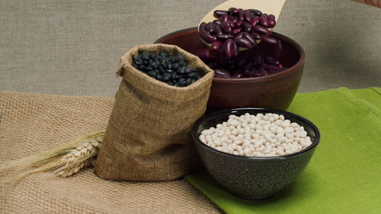 Scooping Red Beans with a Wooden Spoon Amidst Various Legumes