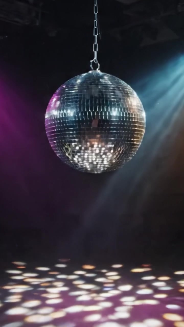 En fængslende diskokugle, der funkler under farverige lys, skaber en magisk atmosfære og kaster blændende refleksioner på dansegulvet i en natlig setting