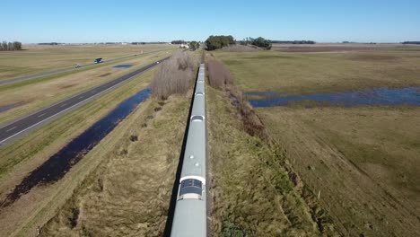 train moving through rural landscape, fields and a road beside, near buenos aires