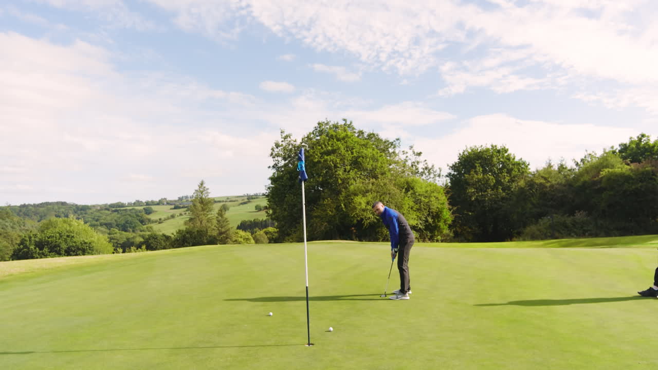 Male golf players playing golf together, hitting the ball with club on a golf course on a sunny day
