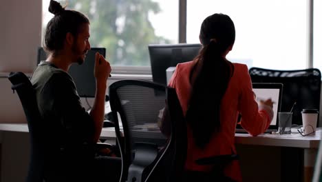 business colleagues interacting with each other at desk in office 4k