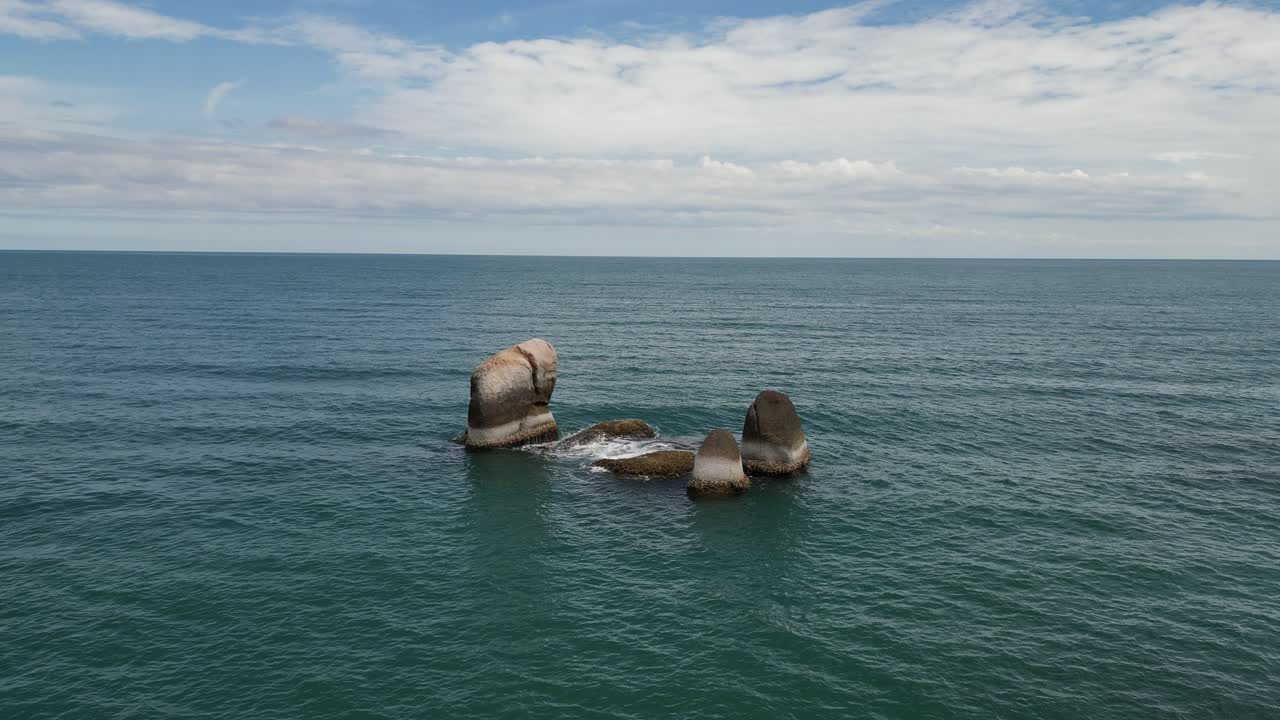 해수면 위 에 큰 바위 가 물 물결 에 부 ⁇ 히고 있는 모습 을 찍은 사진