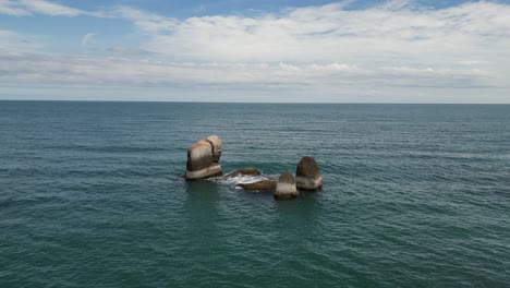 fotografía de grandes rocas levantadas por encima del nivel del mar golpeadas por las olas de agua
