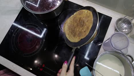 The-process-of-cooking-homemade-pancakes.-Woman-puts-pancake-from-pan-to-plate