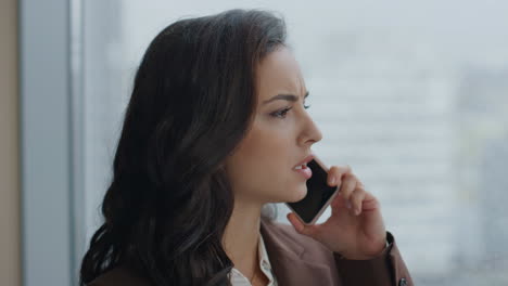 gerente de oficina hablando por teléfono de pie en la ventana de primer plano. mujer usando el teléfono.