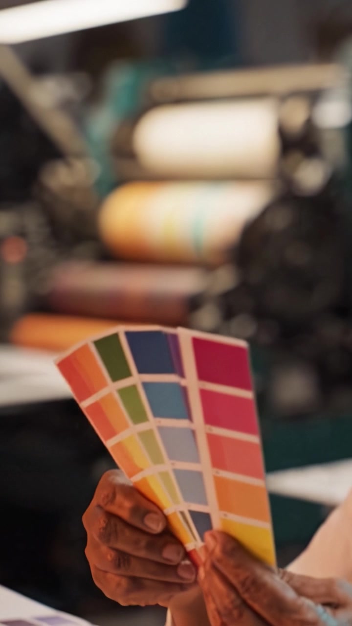 Examining a Detailed Color Palette While Working in a Colorful Print Shop with Various Printing Machines and Tools in the Background
