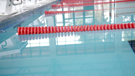 swimming pool with red lane dividers reflecting in clear water, copy space