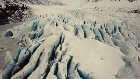 Glacier-tongue-in-Iceland-filmed-by-drone-with-different-cinematic-movements,-showing-a-cloudy,-dramatic-concept-in-wintery-conditions