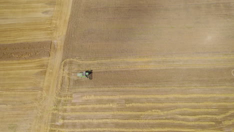 Máquina-De-Tractor-De-Corte-De-Cosecha-Trabajando-En-Suelo-Agrícola-Seco-Y-Dorado-En-Tierras-Agrícolas,-Paisaje-Rural-Y-Agricultura,-Vista-Aérea-De-Arriba-Hacia-Abajo