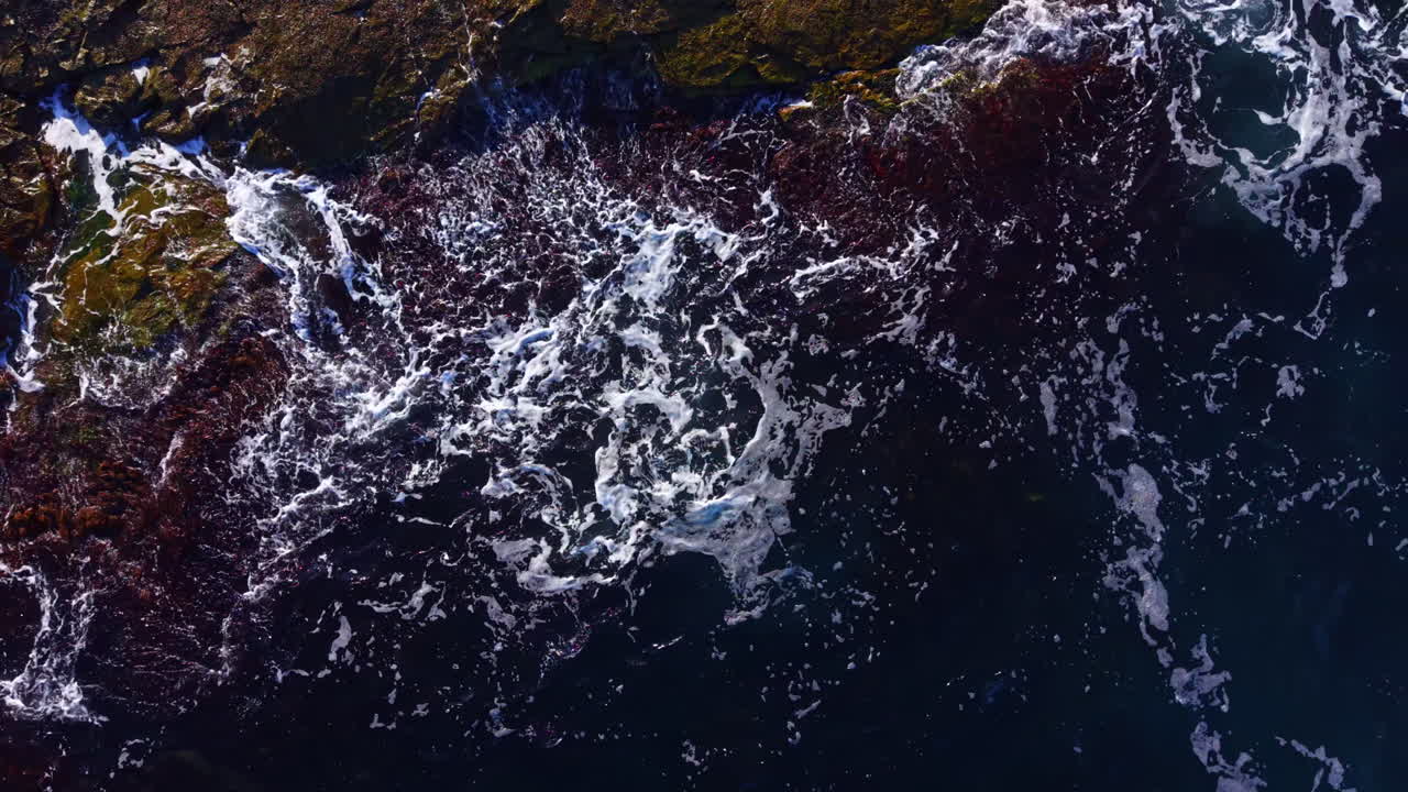 Waves dance over rocky shores at twilight, revealing nature's untamed beauty in a vivid tapestry of colors and textures