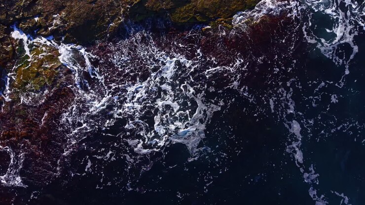 Waves dance over rocky shores at twilight, revealing nature's untamed beauty in a vivid tapestry of colors and textures