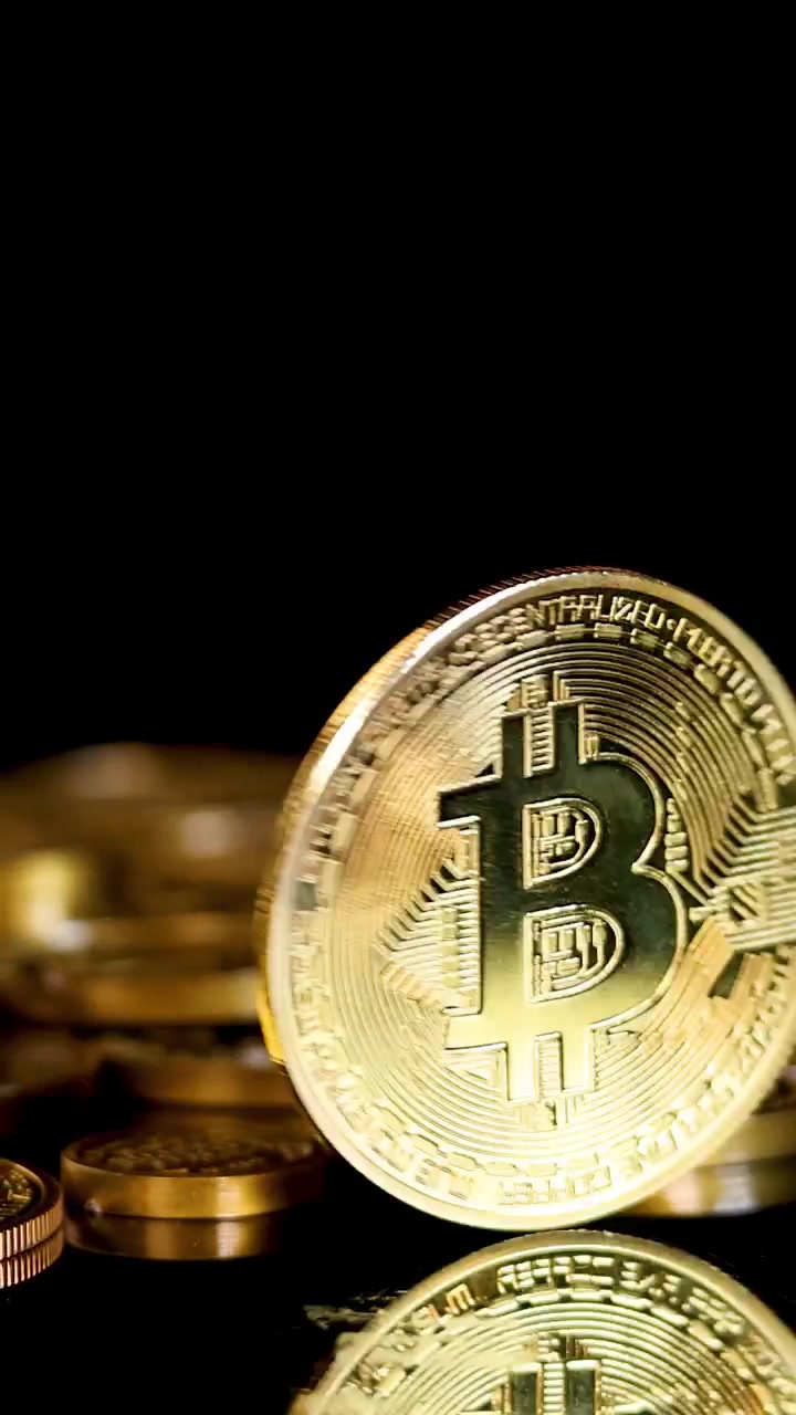 Moeda de criptomoeda dourada gira e cai entre moedas empilhadas, com iluminação dramática, em close-up, sobre um fundo escuro.
