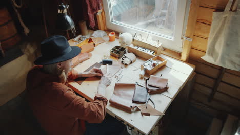 leather craftsman working at desk in workshop