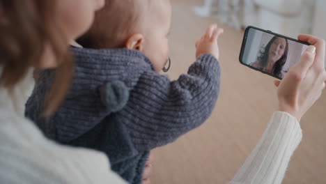 young mother and baby having video chat with grandmother using smartphone waving at grandchild enjoying family connection chatting on mobile phone screen 4k