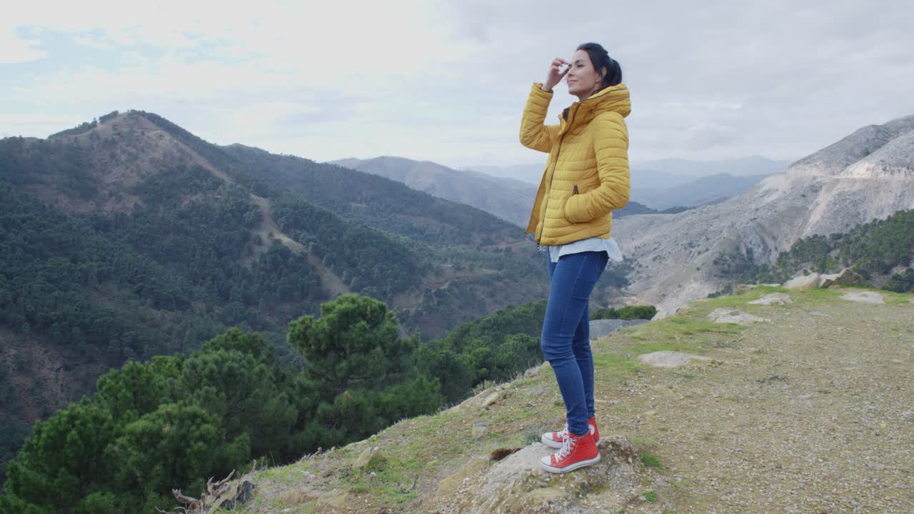 산 계곡 근처 에 있는 노란 코트 를 입은 여자