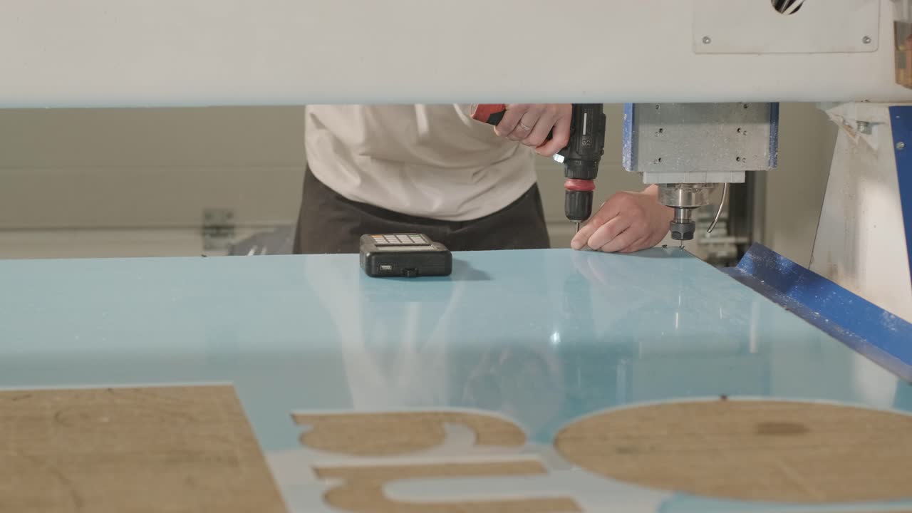 공장에서 광고 표지판의 생산. 스크류 드라이버는 스크류를 단단히.