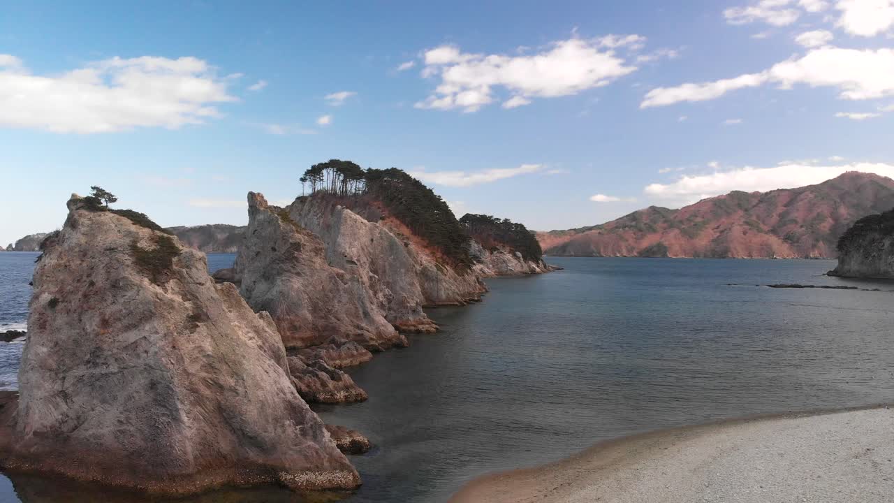 Ripresa aerea ascendente sulla spiaggia di Jodagahama in Giappone in una giornata parzialmente nuvolosa