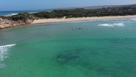 Rotating-aerial-of-group-of-kids-learning-to-surf-in-protected-bay