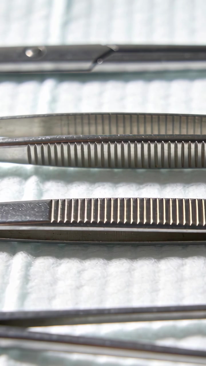 Vertical video: Moving camera, shifting focus and light, showing metal forceps on pad to show grips