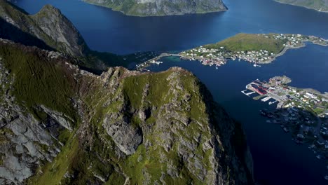 flying around the peak of a mountain overlooking the little town reine, the ocean and mountains in the background