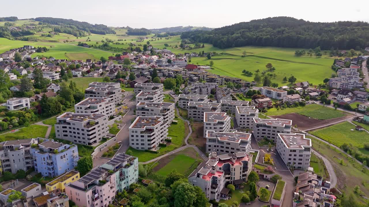 Green rooftop with installed solar panels on top of luxury apartment blocks in Swiss town. Aerial orbit wide shot. Sunny day in summer. Wil, Switzerland. Aerial orbit wide shot.