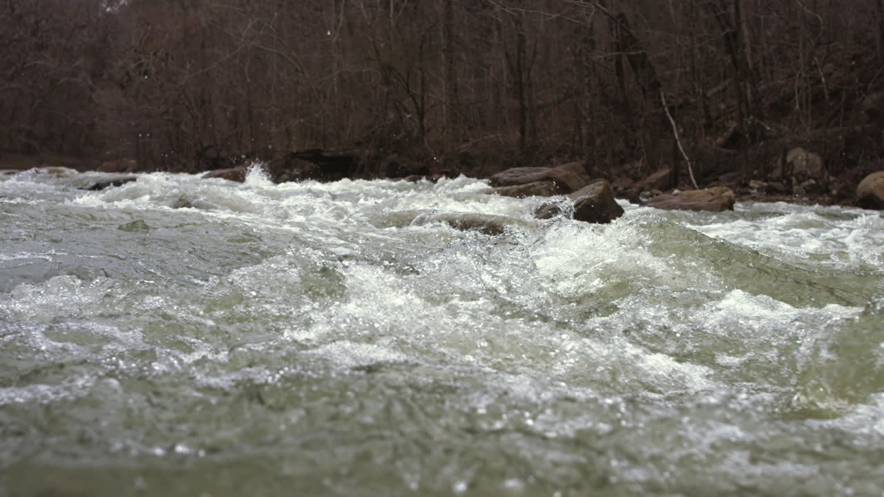 Slow motion camera pan across a very full creek that has rocks and rapids in Chattanooga, TN.