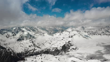 air flight through mountain clouds over beautiful snow-capped peaks of mountains and glaciers.