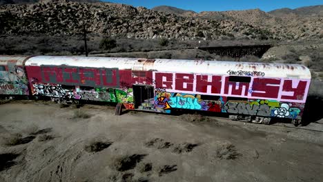 train car covered with spray paint on abandoned railroad line in mountains