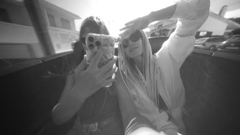 two young women taking a selfie in a car on a sunny day