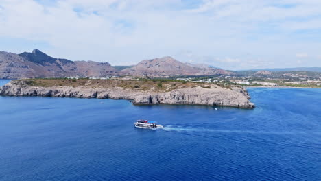 drone tracking a tour boat on the coast the rhodes island, sunny day in greece