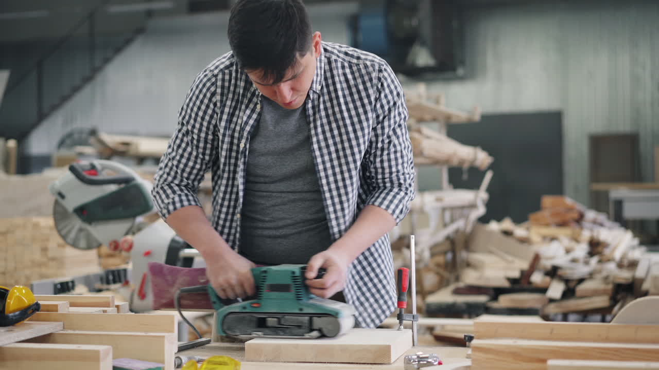 Carpenter using a belt sander in a workshop