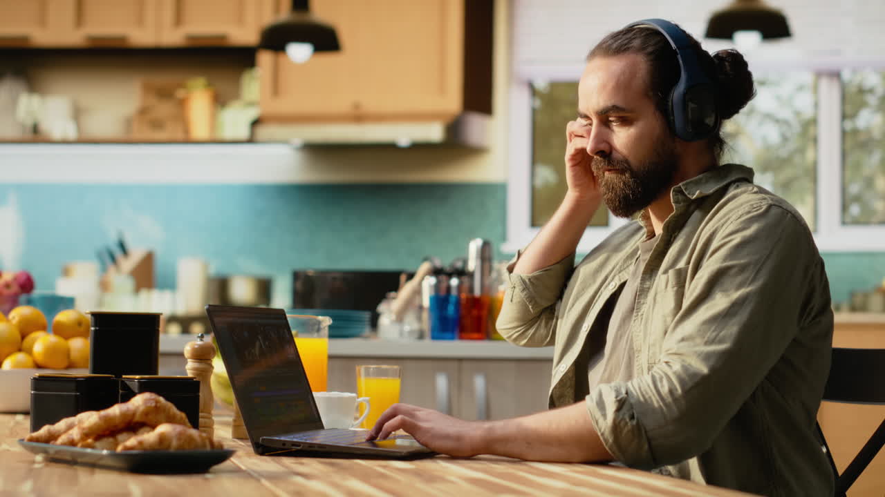 Creative editor producing cinematic footage on laptop in kitchen environment