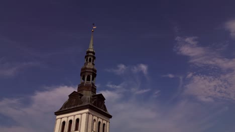 a majestic drone view captures niguliste church standing tall against a bright blue sky in tallinn estonia showcasing its medieval spire elegant stonework and historic architectural beauty