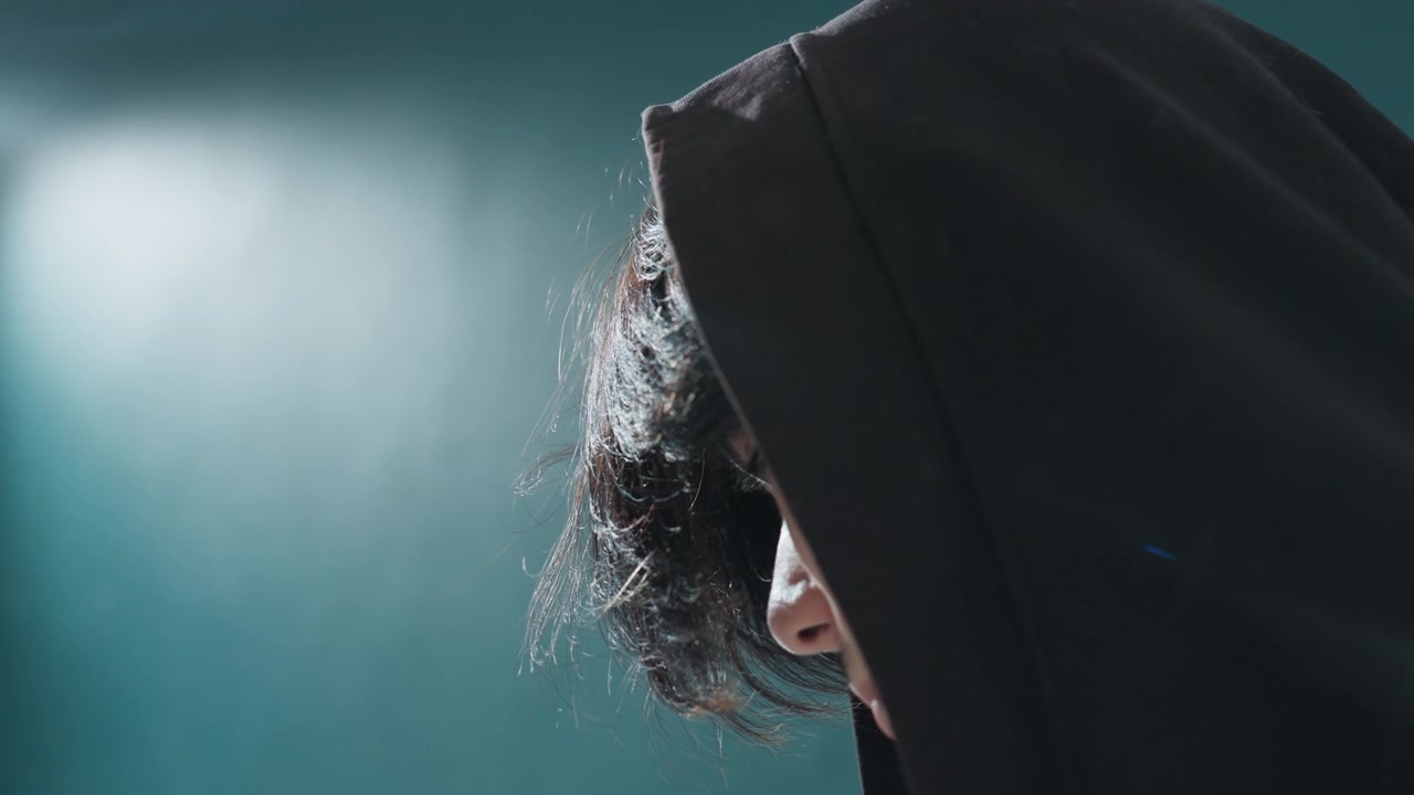 Ritratto giovanile con felpa con cappuccio. Vista di profilo di un adolescente con felpa che cattura la luce riflessa. Profilo laterale in stile cinematografico di una persona giovane con felpa e capelli acconciati in un'atmosfera da studio artistico.