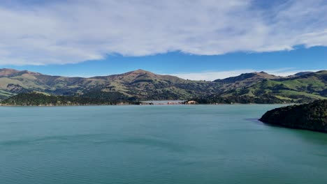 aerial footage captures akaroa's serene lake, lush hills, and expansive sky under natural daylight