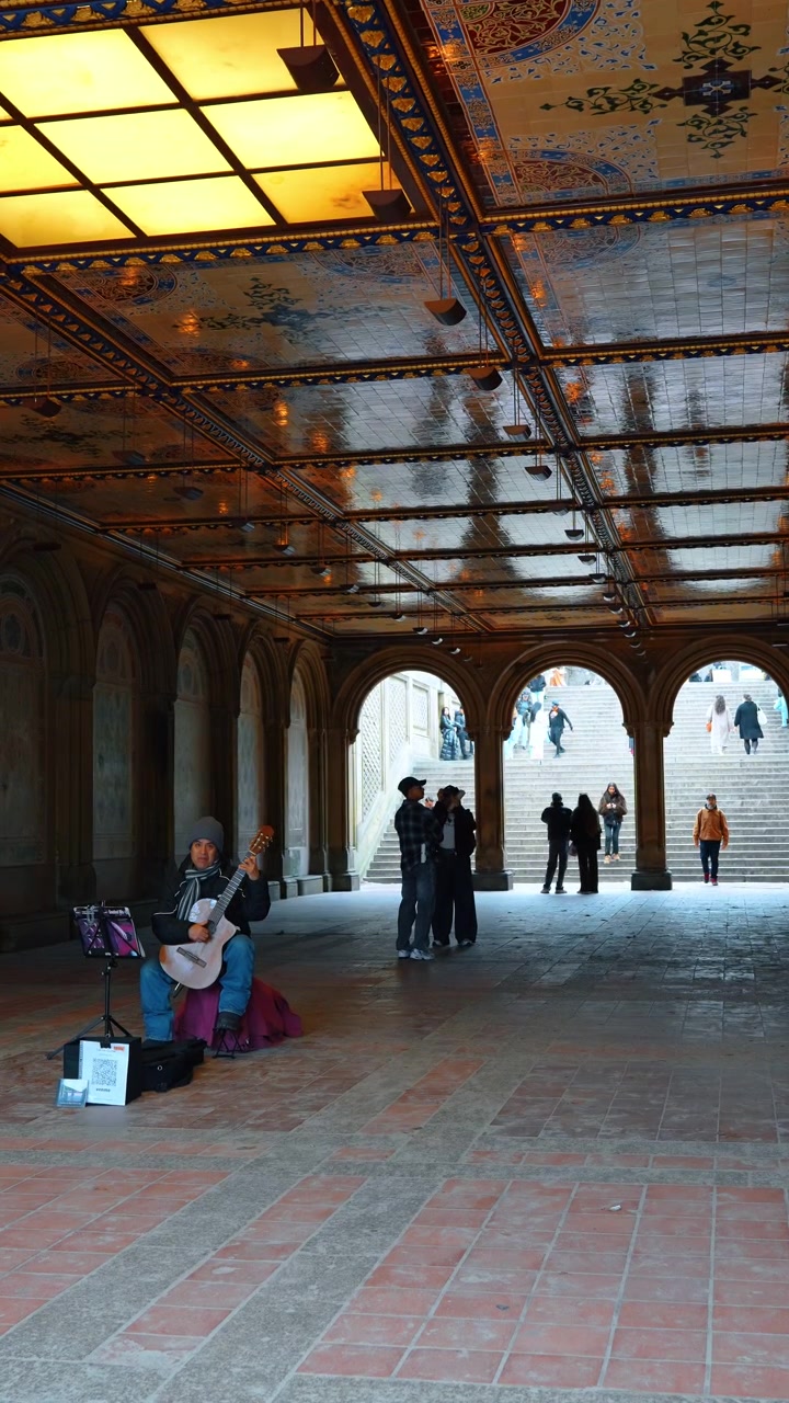 นิวยอร์ก สหรัฐอเมริกา 24 มีนาคม 2026: นักดนตรีกำลังเล่นกีตาร์ที่ Bethesda Terrace Arcade NYC นักแสดงข้างถนนกำลังเล่นกีตาร์โปร่งใต้เพดานโค้งกระเบื้องของระเบียง Central Park ที่มีผู้คน