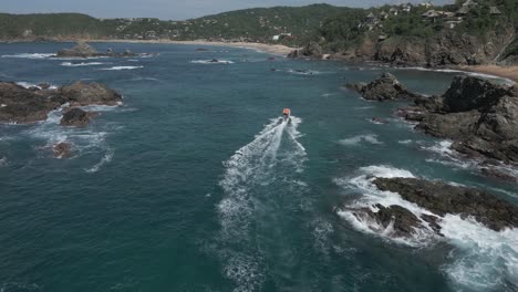 Tourism-boat-motors-over-clear-turquoise-water-into-rocky-ocean-bay