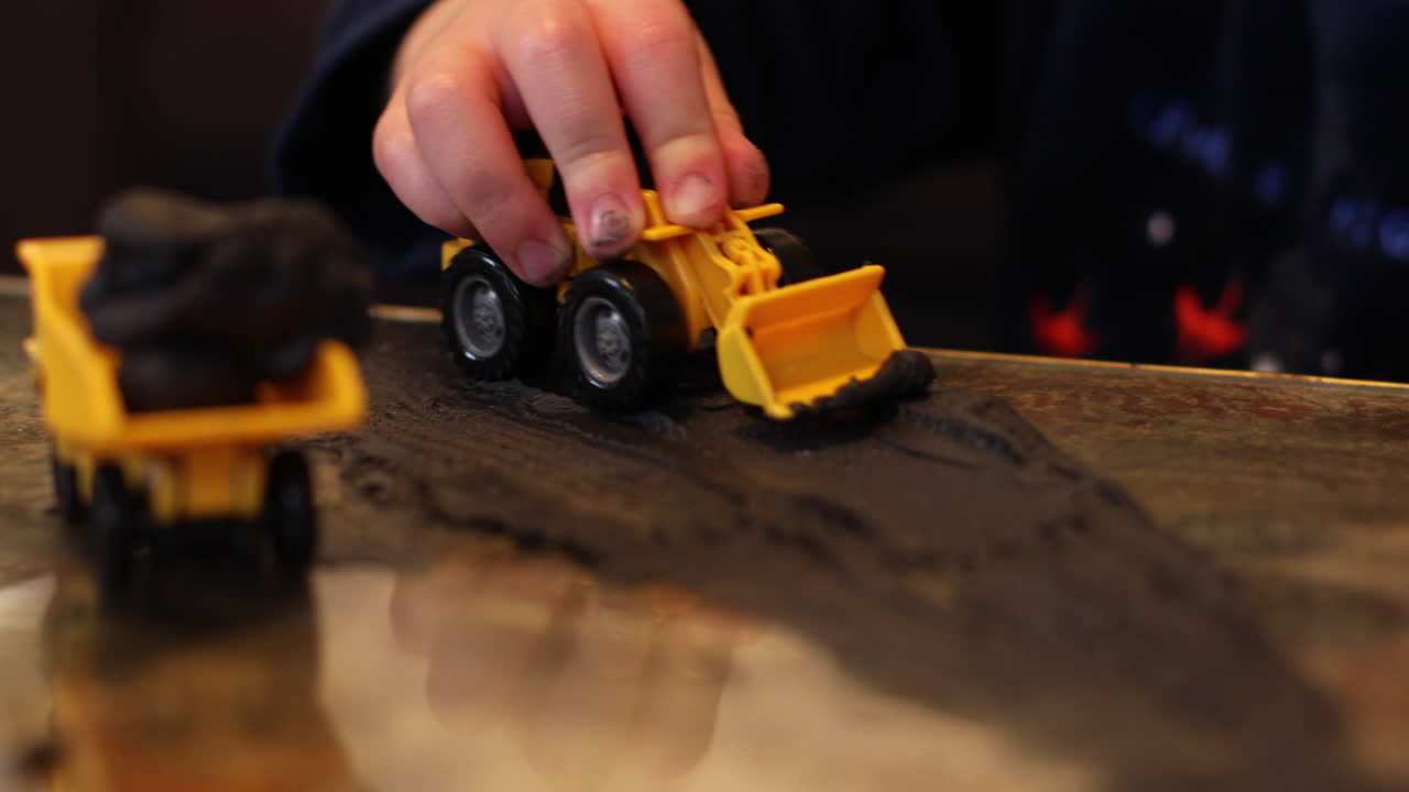 봉쇄 기간 동안 견인 굴착기와 점토를 가지고 노는 아이의 손 클로즈업