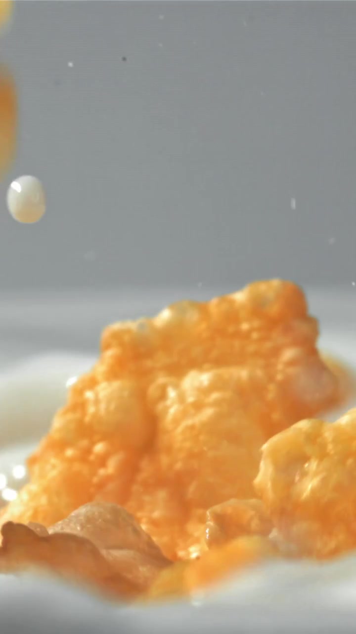 Cornflakes croccanti che cadono nel latte fresco al rallentatore