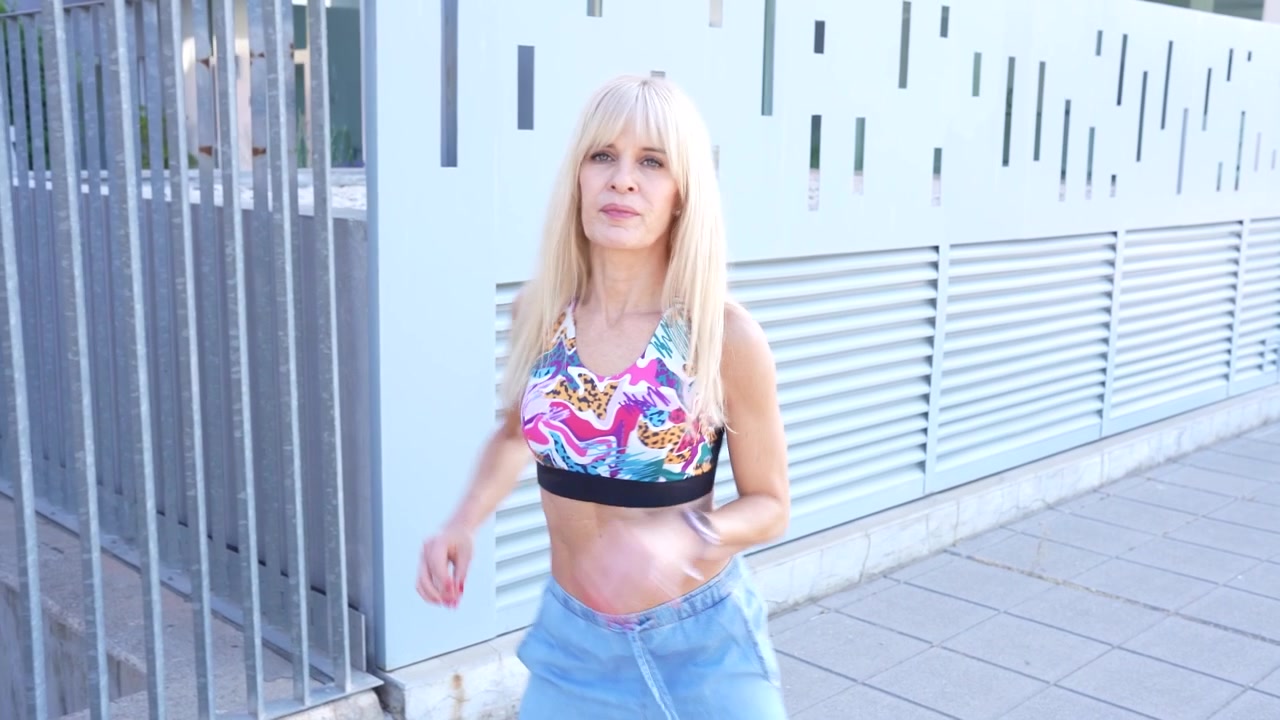 Una giovane donna cammina all'aperto vicino a un edificio moderno indossando un abbigliamento casual