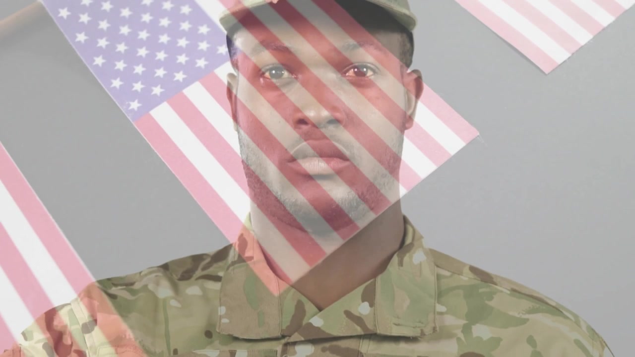 Soldato in uniforme mimetica che tiene una bandiera americana piegata