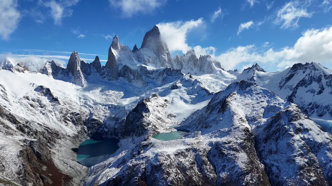 Drone aereo della catena montuosa del Cerro Fitz Roy in Patagonia, Argentina, che mostra cime innevate, creste frastagliate e laghi glaciali turchesi sotto un cielo azzurro in un paesaggio montano spettacolare e un terreno freddo