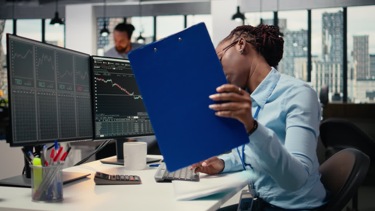 Equity analyst in office reviews quarterly earnings paperwork, making calls