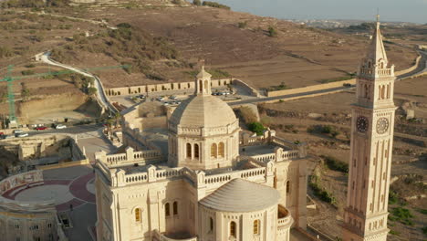 Iglesia-De-Ta-Pinu-Basílica-De-Color-Beige-Arena-En-La-Isla-Mediterránea-De-Gozo,-Malta-Bajo-La-Hermosa-Luz-Del-Sol,-Diapositiva-Aérea-A-La-Izquierda