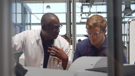 engineer teaching apprentice how to use machine in factory