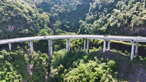 aerial view of a long highway bridge winding through lush green forest