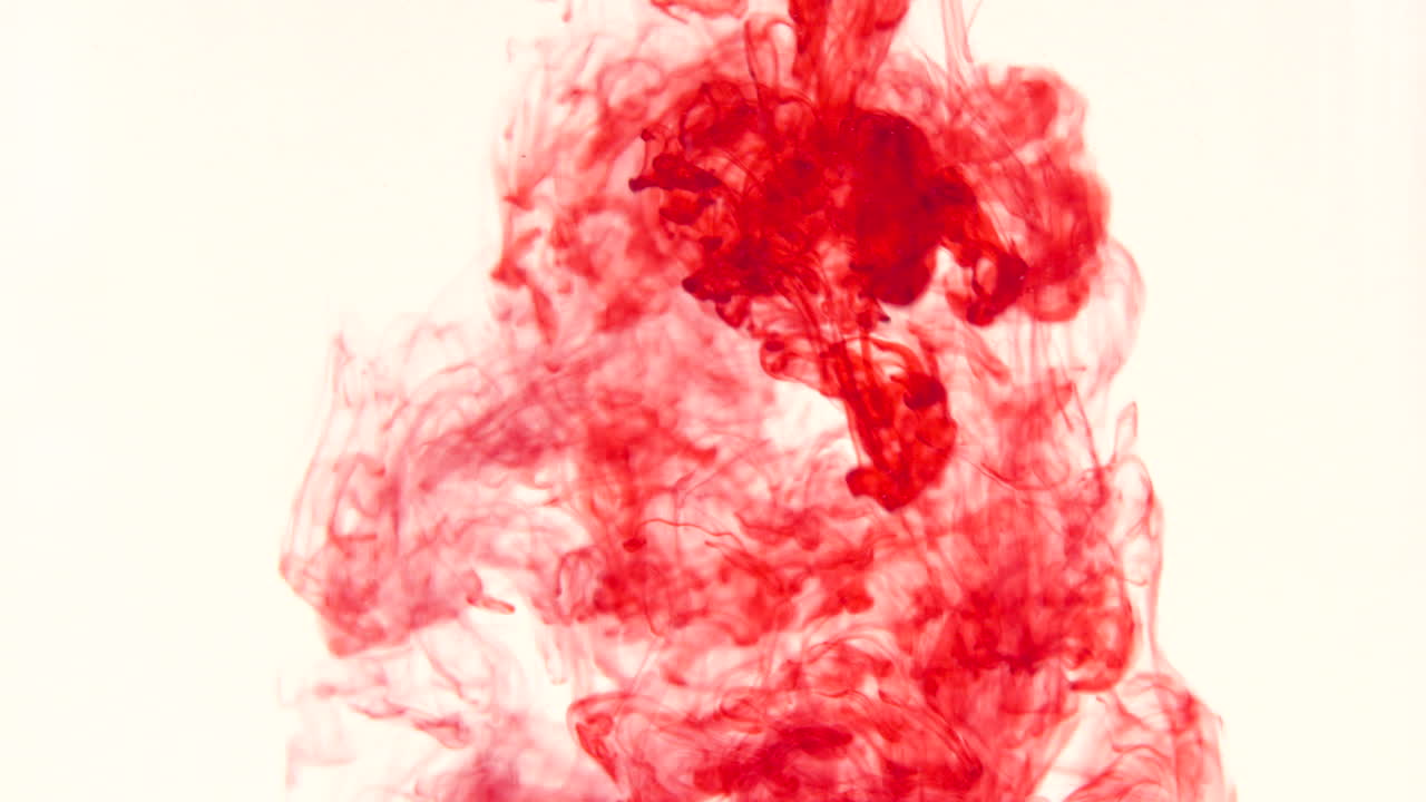 Red food coloring dropping and swirling in water